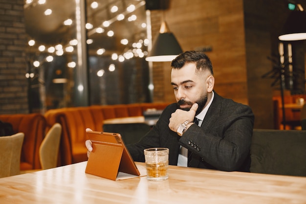 Handsome man in a black suit, working in a cafe