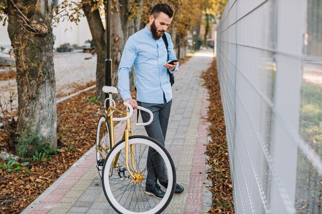 Handsome man browsing smartphone near fence