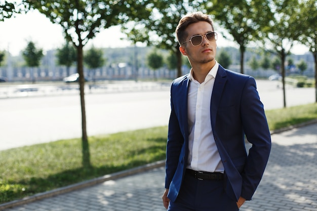 Handsome man in a business suit walks along the street in a sunny day