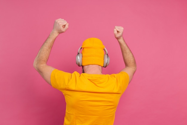 Free Photo handsome man in casual dancing with headphones isolated on pink background