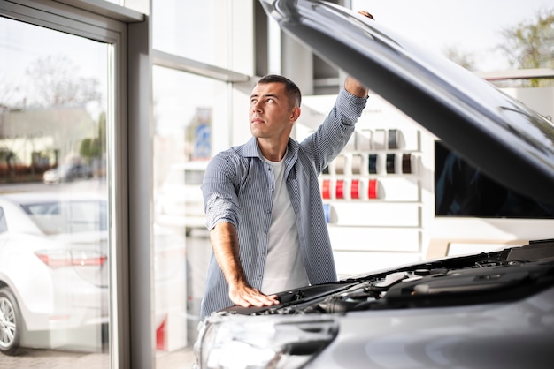 Handsome man checking a car at dealership