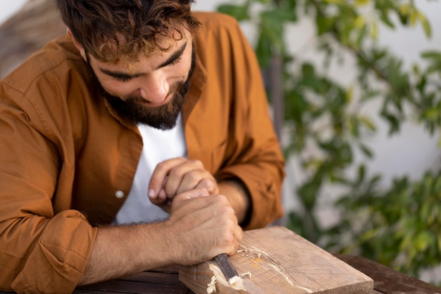 Free Photo handsome man engraving in wood outdoors