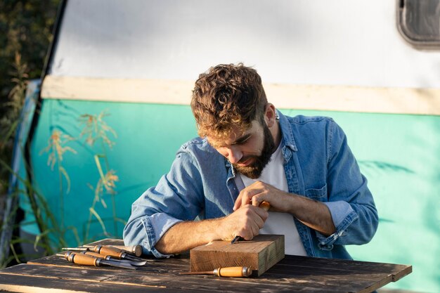 Free Photo handsome man engraving in wood outdoors