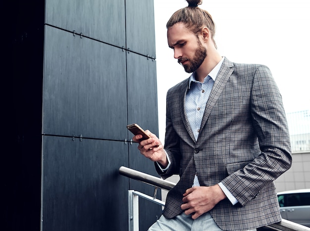 Handsome man in gray checkered suit with smartphone