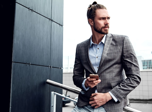 Handsome man in gray checkered suit with smartphone