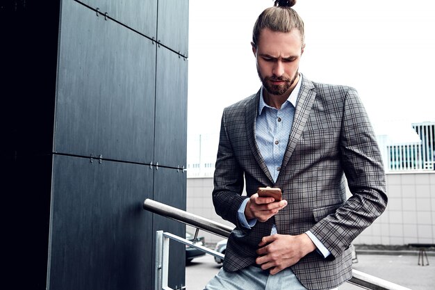 Handsome man in gray checkered suit with smartphone