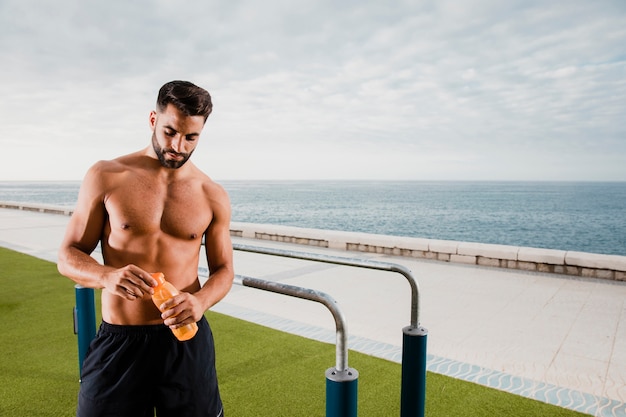 Handsome man having a break and hydrate while workout