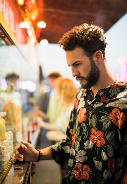 Free Photo handsome man having a snack at funfair