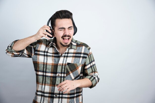 handsome man in headphones standing and listening to song.