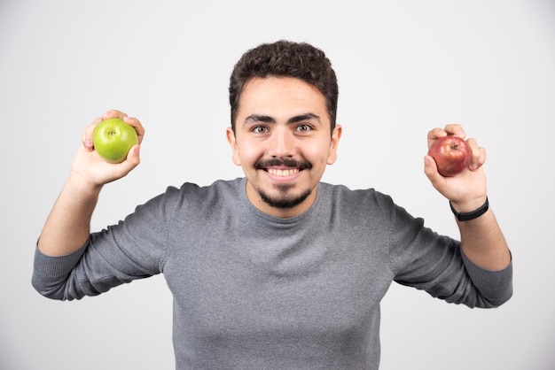 Handsome man holding apples on gray.