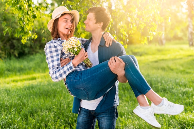 Handsome man holding happy woman on hands