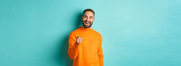 Free photo handsome man laughing and pointing at camera nodding in approval agree with you standing over light