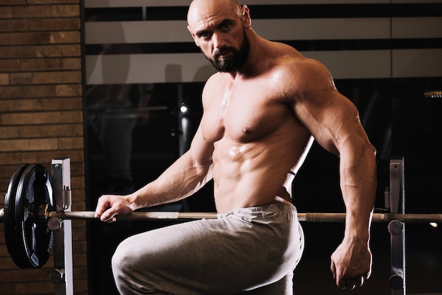 Handsome man posing near barbell