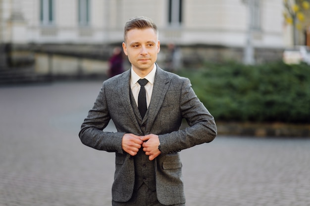 Handsome man posing in wedding suit in the streets