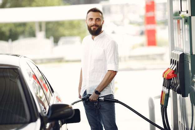 Free photo handsome man pours gasoline into tank of car