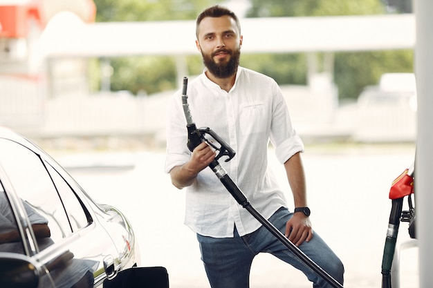 Free Photo handsome man pours gasoline into tank of car