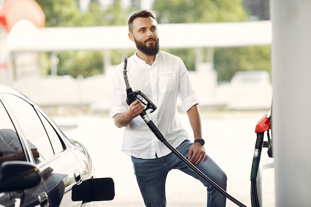 Handsome man pours gasoline into tank of car