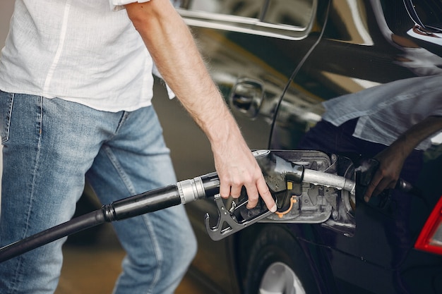 Free photo handsome man pours gasoline into tank of car