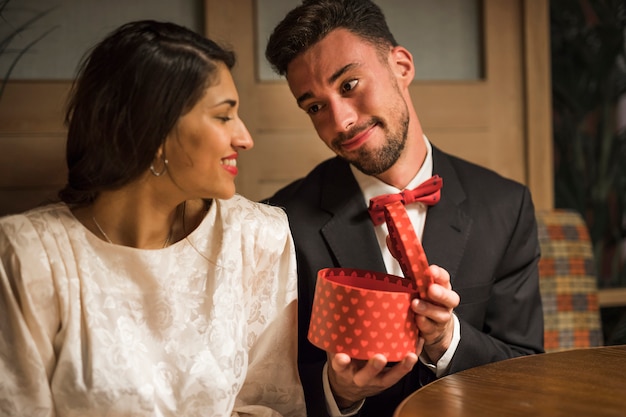 Handsome man presenting gift box to young happy woman