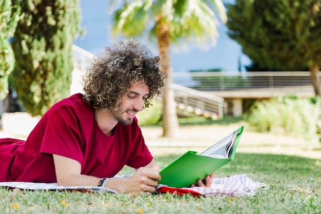 Free photo handsome man reading book in park