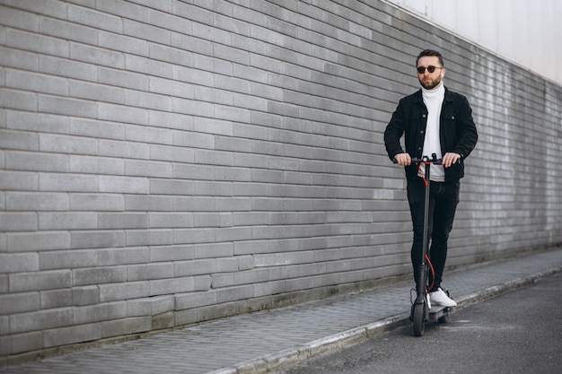 Free photo handsome man riding in town on scooter