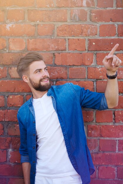 Handsome man showing on brick wall