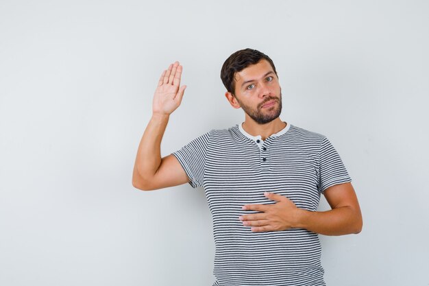 Handsome man showing his palm in t-shirt and looking confident , front view.