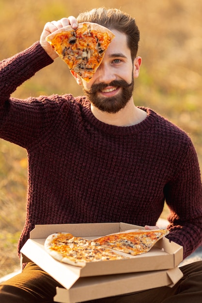 Free photo handsome man showing a slice of pizza