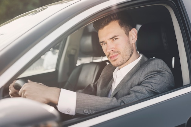 Free photo handsome man sitting in the car looking at camera