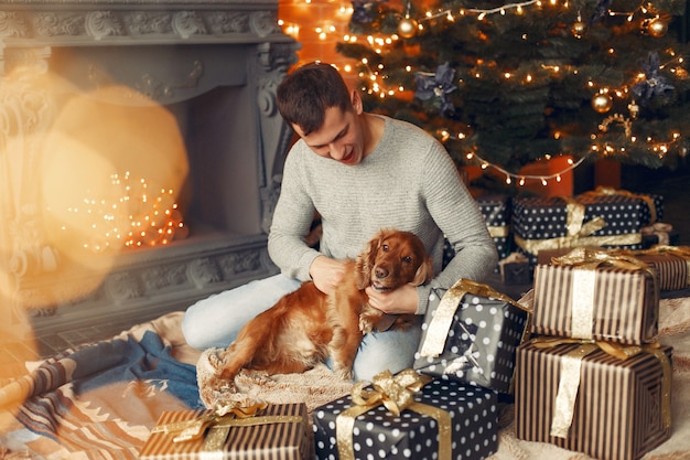 Free Photo handsome man sitting hear fireplace with a dog