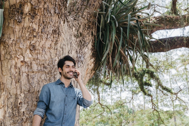 Handsome man speaking on phone in park