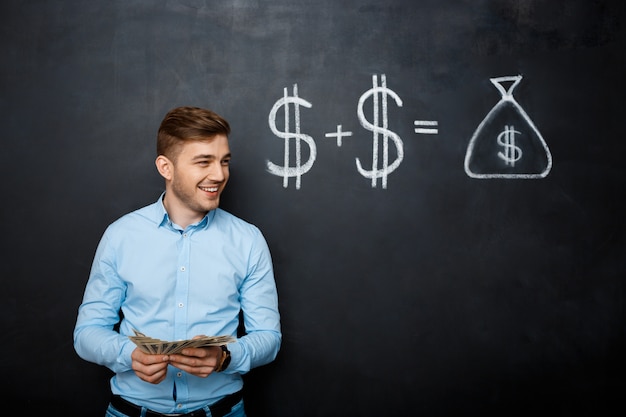 Free photo handsome man standing over blackboard  with drawn dollar concept