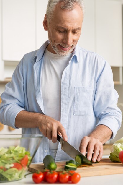 Handsome man standing at the kitchen using laptop and cooking