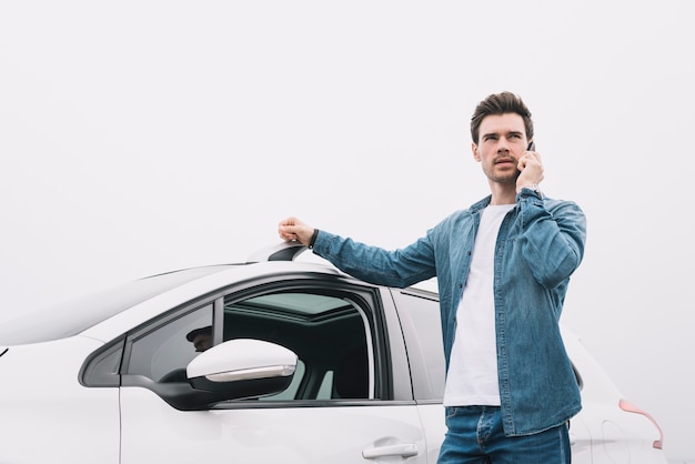 Free photo handsome man standing near the car talking on cellphone