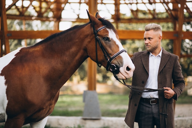 Handsome man in suit at ranch by horse