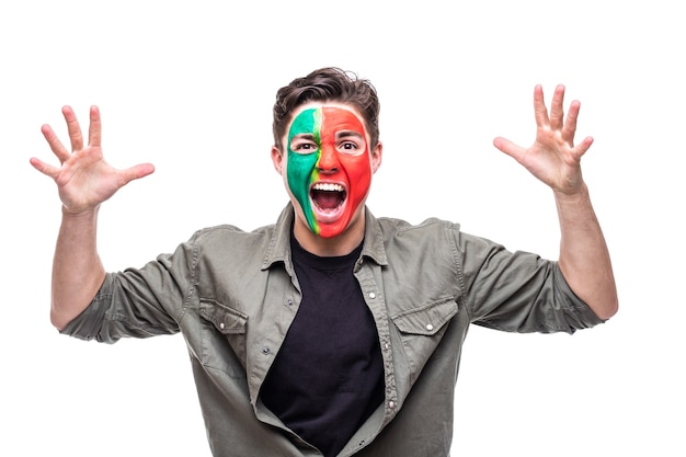 Free Photo handsome man supporter fan of portugal national team painted flag face get happy victory screaming into a camera. fans emotions.