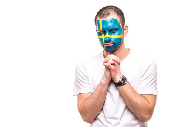 Handsome man supporter fan of Sweden national team painted flag face get unhappy sad frustrated emoitions into a camera. Fans emotions.