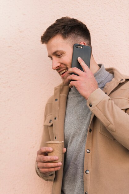 Handsome man talking on the phone and holding coffee cup