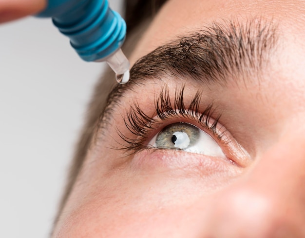 Handsome man using eye drops close-up