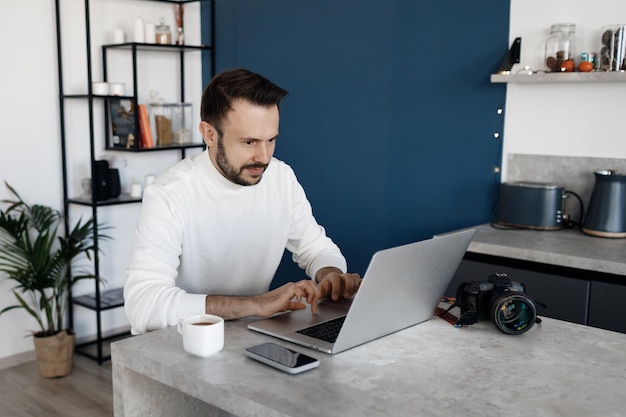 handsome man using laptop at home at kitchen