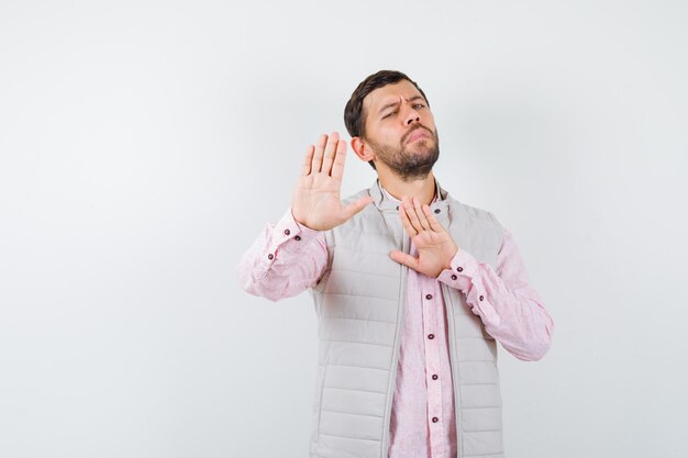 Handsome man in vest, shirt showing stop gesture and looking irritated ,