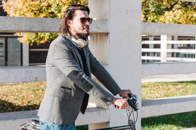 Free Photo handsome man wearing sunglasses riding bicycle