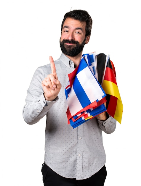 Free photo handsome man with beard holding many flags and counting one