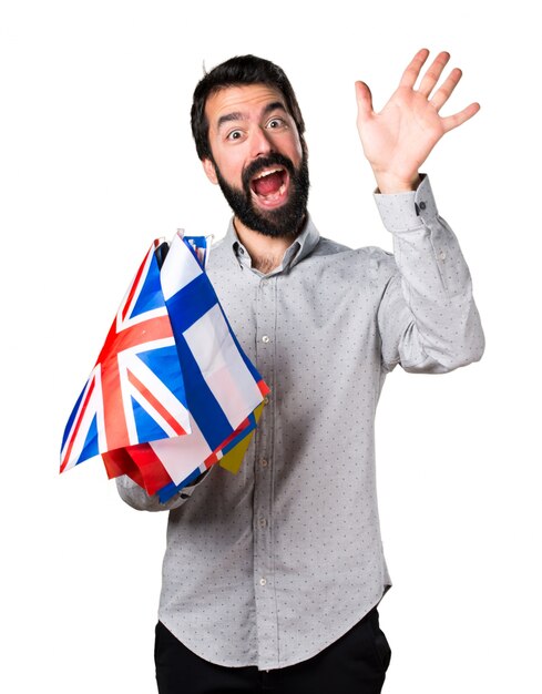 Handsome man with beard holding many flags and saluting