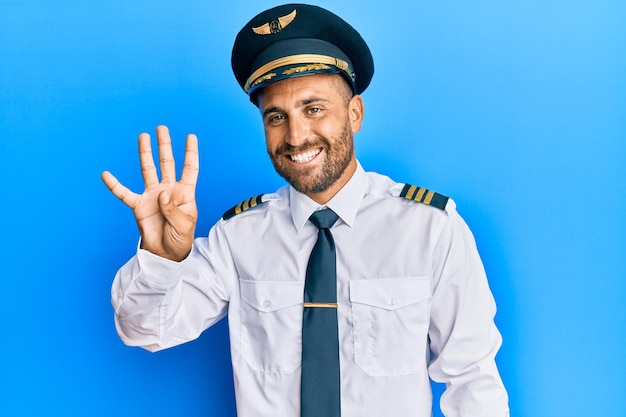 Free photo handsome man with beard wearing airplane pilot uniform showing and pointing up with fingers number four while smiling confident and happy