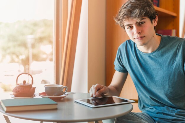 Handsome man with gadget sitting at table