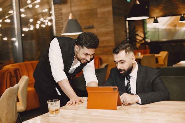 Handsome men in a black suits, working in a cafe