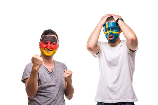 Handsome men supporters loyal fans of Sweden national team And Germany with painted flag face. Germany win, Sweden lose. Fans emotions.