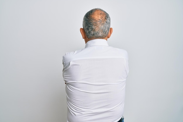 Free photo handsome senior man wearing casual white shirt standing backwards looking away with crossed arms