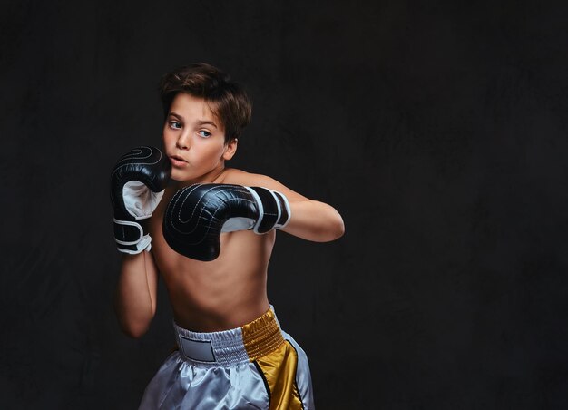 Handsome shirtless young boxer during boxing exercises, focused on process with serious concentrated facial.